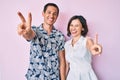 Beautiful couple wearing casual clothes smiling with tongue out showing fingers of both hands doing victory sign Royalty Free Stock Photo