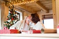 Senior couple in sweaters wrapping Christmas gifts together.