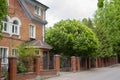 Beautiful courtyard with a brick red house, forged gates and lush flowering chestnut. Pretty country house patio, blooming green