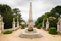 Beautiful courtyard with an ornate fountain and obelisk surrounded by classical statues and greenery high above a European village Royalty Free Stock Photo