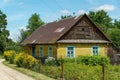 A beautiful cozy house in the village and a flower garden. A yellow wooden house near a dirt road in the distance from the Royalty Free Stock Photo