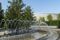 Beautiful Crater Fountain Water in sparkling arc fall on stone. People rest in shade of Evergreen Magnolia Grandiflora Royalty Free Stock Photo