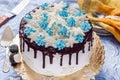 Beautiful cream cake decorated with chocolate leaks, cream and sugar snowflakes from mastic