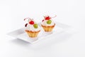 Beautiful cream cakes with cherries and grapes on a plate on a white background