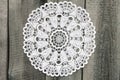 Beautiful white crochet doily on old wooden background