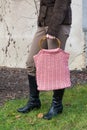 Beautiful crocheted old pink handbag with person behind the wall in autumn