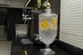 Beautiful crystal decanter with water savored with tropical fruits next to a cooler with beer and glasses