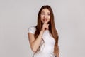 Beautiful cunning woman smiling, showing gesture secret sign with finger near her lips. Royalty Free Stock Photo