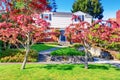 Beautiful curb appeal of brick house with well kept lawn and red trees in the front garden. Royalty Free Stock Photo