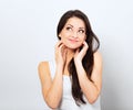 Beautiful curious smiling woman with amazing eyes holding the head the hands thinking and looking up in casual white t-shirt and Royalty Free Stock Photo