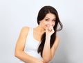 Beautiful curious smiling woman holding the head the hands thinking and looking up in casual white t-shirt and long hair on blue