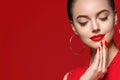 Beautiful curle hair female in red with red lips and dress manicure, beauty rose over red background Royalty Free Stock Photo