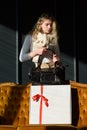 beautiful curly blond hair woman posing with a small black shopper bag near vintage volor sofa. giftbox