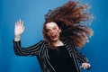 beautiful curly girl on a blue background with flying hair happy