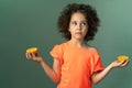 beautiful curly girl with oranges in two hands with brown eyes