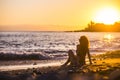 Beautiful curly hair nice model woman middle age young sitting at the beach enjoying the freedom and the relaxed sunset with Royalty Free Stock Photo