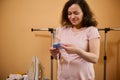 Beautiful pregnant woman smiling while holding ironed baby cap for newborn, in dressing room or ironing room at home Royalty Free Stock Photo