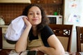 Beautiful young woman housewife, baker confectioner in chef& x27;s apron, sitting at table in home kitchen, smiling at