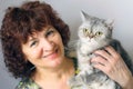 A woman holding a cat of British breed