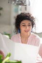 Beautiful curly-haired woman looking trough the price list and looking involved