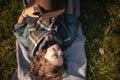 Portrait of beautiful curly-haired young woman with closed eyes in an autumn park in a hat and a plaid scarf lying on the grass Royalty Free Stock Photo