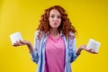 Beautiful curly redhead ginger woman choosing eco toilet paper roll on yellow color background Royalty Free Stock Photo