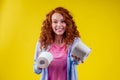 Beautiful curly redhead ginger woman choosing eco toilet paper roll on yellow color background Royalty Free Stock Photo