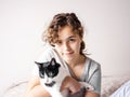 Beautiful curly teenager girl in the bed hugs her cat. Pet love. Animal care Royalty Free Stock Photo