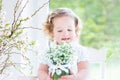 Beautiful curly toddler girl holding first spring flowers Royalty Free Stock Photo