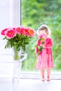 Beautiful curly toddler girl playing with peony flowers Royalty Free Stock Photo