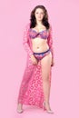 Beautiful curvy young woman wearing colorful bikini with gown on pink background. Royalty Free Stock Photo