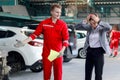 Beautiful customer woman seriously discussing with mechanic man in red uniform about cost of repairing vehicle automobile, auto Royalty Free Stock Photo