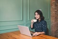 Beautiful cute asian young businesswoman in the cafe, using laptop and drinking coffee smiling