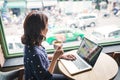 Beautiful cute asian young businesswoman in the cafe, using laptop and drinking coffee smiling