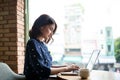 Beautiful cute asian young businesswoman in the cafe, using laptop and drinking coffee smiling