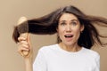 beautiful attractive middle-aged brunette woman combing her long hair with a wooden comb while standing in a white poppy Royalty Free Stock Photo