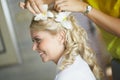 Beautiful, cute blond bride doing hair with flowers before wedding day. Long lashes, white flowers, smilling and happy.