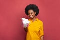 Beautiful cute brunette woman giving pink gift box on bright red banner background Royalty Free Stock Photo