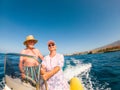 Beautiful and cute couple of seniors or old people in the middle of the sea driving and discovering new places with small boat. Royalty Free Stock Photo