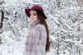 Beautiful cute elegant girl in a fur coat and hat walking in the winter forest bright frosty morning Royalty Free Stock Photo