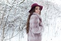 Beautiful cute elegant girl in a fur coat and hat walking in the winter forest bright frosty morning