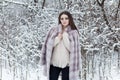 Beautiful cute elegant girl in a fur coat walks in the winter forest bright frosty morning Royalty Free Stock Photo