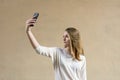 Beautiful cute girl on a beige background. Without anyone. Blond girl with green eyes. She looks at the phone. Businesswoman. The Royalty Free Stock Photo