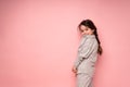 Beautiful cute girl with gathered hair stands sideways on a pink background and looks at the camera Royalty Free Stock Photo