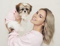 Beautiful cute girl holding a well groomed shih tzu puppy in a pink sweater Royalty Free Stock Photo