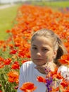 A beautiful cute girl is sitting on a blurry flower field illuminated by the sun. Portrait of a teenage girl looking at the camera