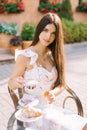 Beautiful cute girl sitting at a table in a street cafe and drinking coffee. Breakfast or lunch Royalty Free Stock Photo