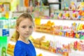 A beautiful and cute girl is standing at the shop window and looking into the camera, near sweet and tasty candies Royalty Free Stock Photo