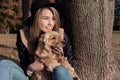 Beautiful cute happy girl in a black hat playing with her dog in a park Royalty Free Stock Photo