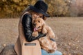 Beautiful cute happy girl in a black hat playing with her dog in a park Royalty Free Stock Photo